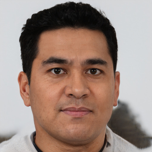 Joyful latino young-adult male with short  brown hair and brown eyes