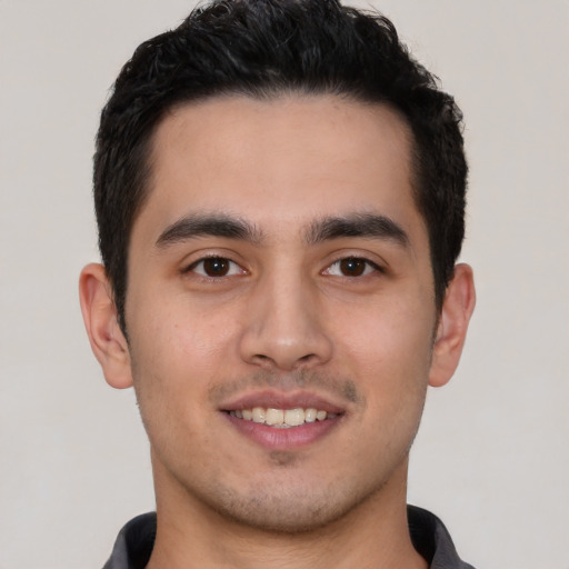 Joyful latino young-adult male with short  black hair and brown eyes