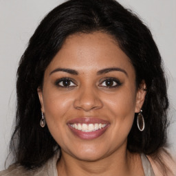 Joyful black young-adult female with long  brown hair and brown eyes