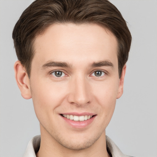 Joyful white young-adult male with short  brown hair and grey eyes