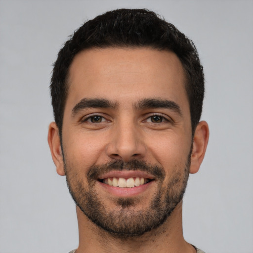 Joyful white young-adult male with short  black hair and brown eyes