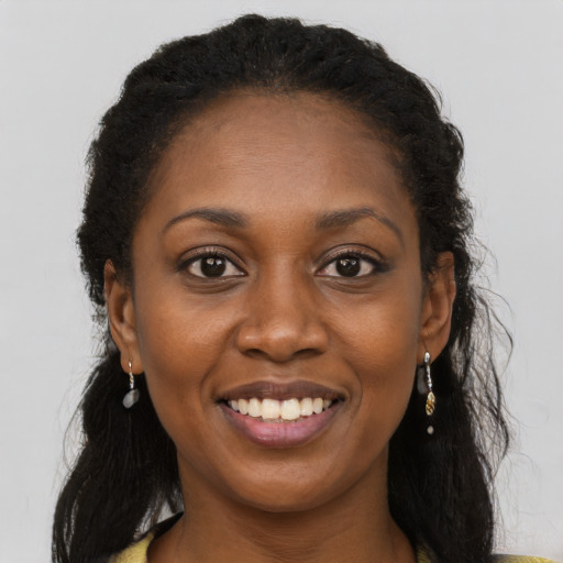 Joyful black young-adult female with long  brown hair and brown eyes