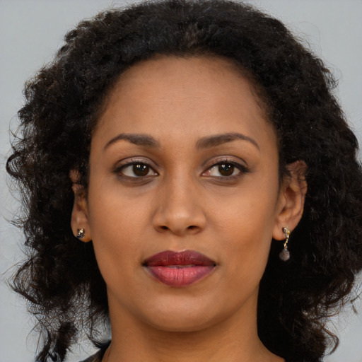 Joyful black young-adult female with long  brown hair and brown eyes