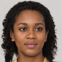 Joyful black young-adult female with long  brown hair and brown eyes