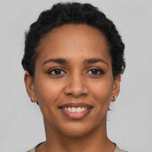 Joyful black young-adult female with short  black hair and brown eyes