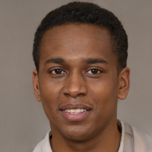 Joyful black young-adult male with short  brown hair and brown eyes