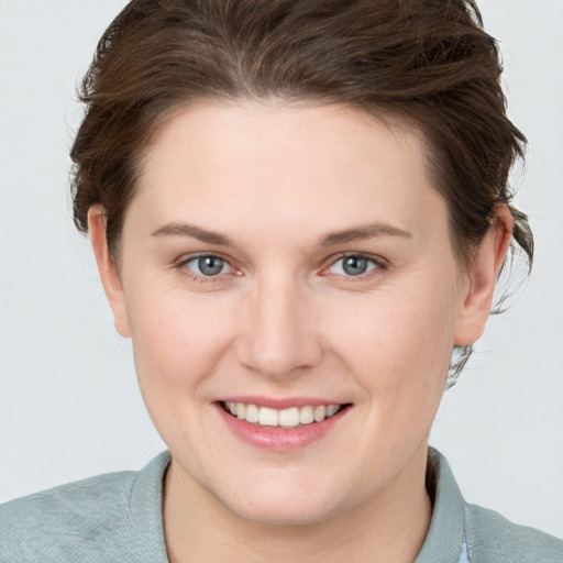 Joyful white young-adult female with medium  brown hair and grey eyes