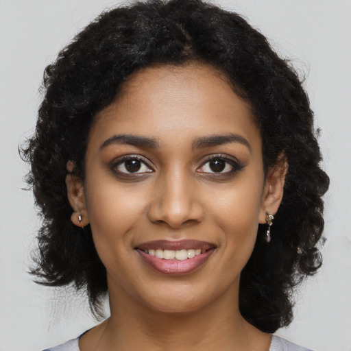 Joyful black young-adult female with long  black hair and brown eyes