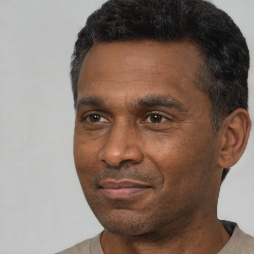 Joyful black adult male with short  black hair and brown eyes