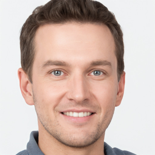 Joyful white young-adult male with short  brown hair and grey eyes