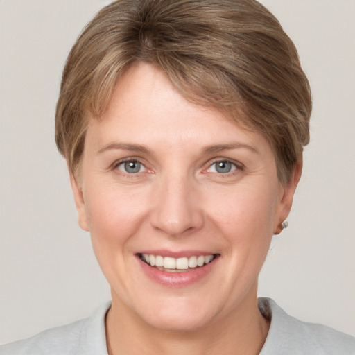 Joyful white young-adult female with short  brown hair and grey eyes