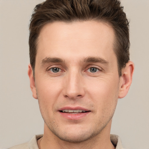 Joyful white young-adult male with short  brown hair and grey eyes