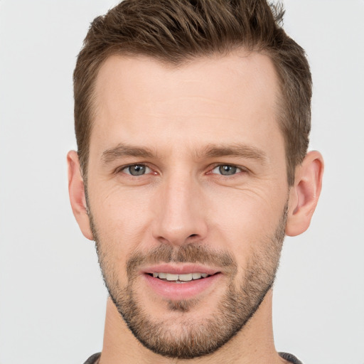 Joyful white young-adult male with short  brown hair and grey eyes