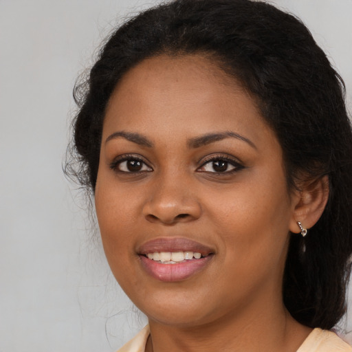 Joyful black young-adult female with long  black hair and brown eyes