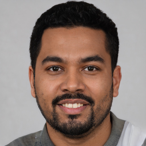 Joyful latino young-adult male with short  black hair and brown eyes