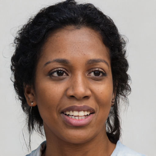 Joyful black young-adult female with long  brown hair and brown eyes