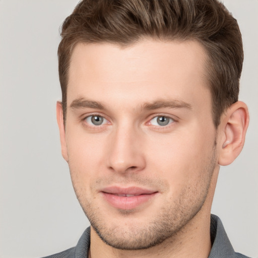 Joyful white young-adult male with short  brown hair and grey eyes