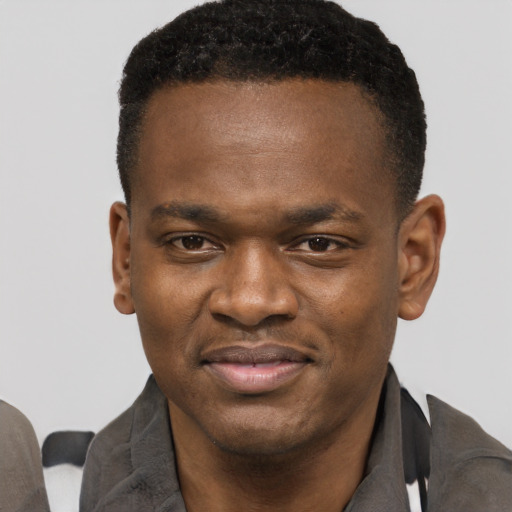 Joyful black young-adult male with short  black hair and brown eyes