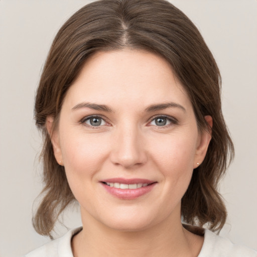 Joyful white young-adult female with medium  brown hair and grey eyes