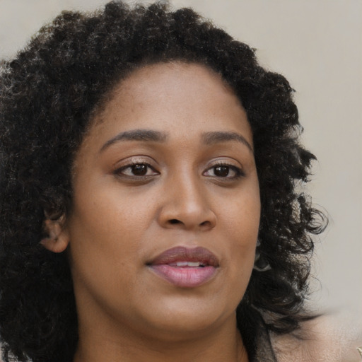 Joyful black young-adult female with long  brown hair and brown eyes