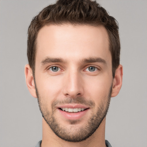 Joyful white young-adult male with short  brown hair and grey eyes