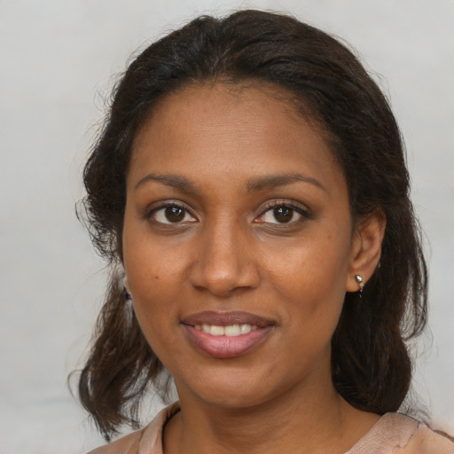 Joyful black adult female with medium  brown hair and brown eyes