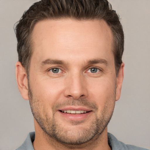 Joyful white adult male with short  brown hair and grey eyes