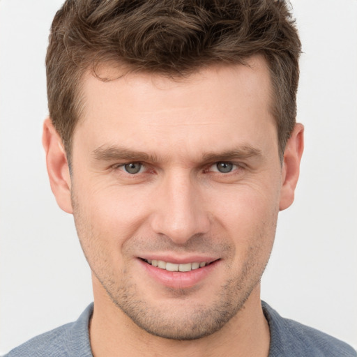 Joyful white young-adult male with short  brown hair and grey eyes