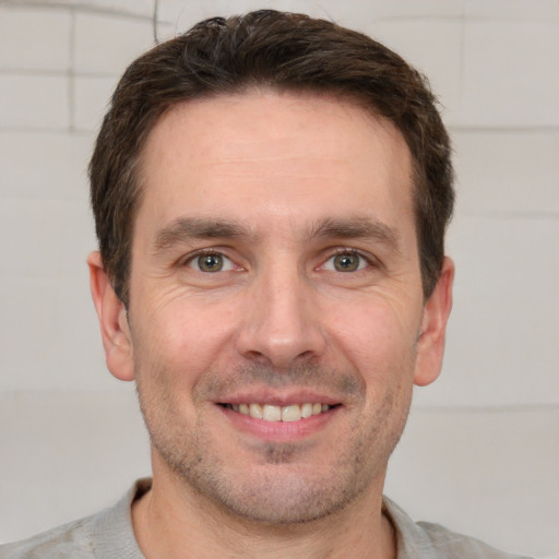 Joyful white adult male with short  brown hair and grey eyes