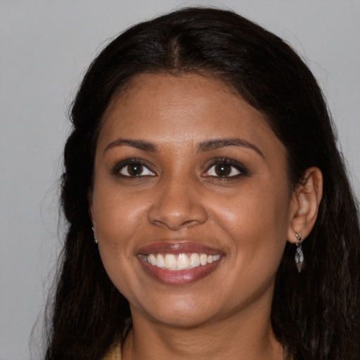 Joyful black young-adult female with long  brown hair and brown eyes