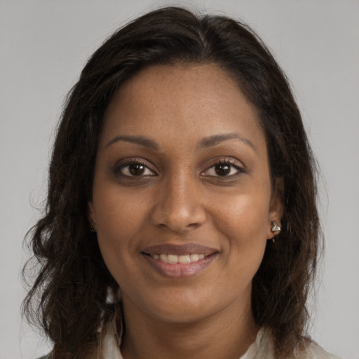 Joyful black young-adult female with long  brown hair and brown eyes