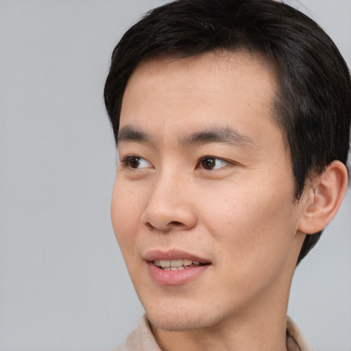 Joyful asian young-adult male with short  brown hair and brown eyes