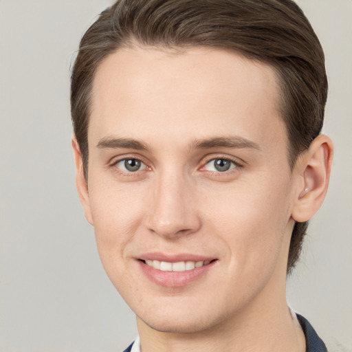 Joyful white young-adult male with short  brown hair and grey eyes