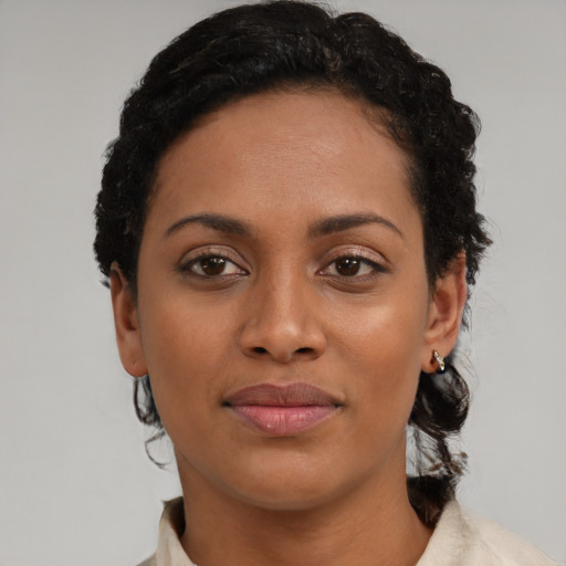 Joyful black young-adult female with short  black hair and brown eyes