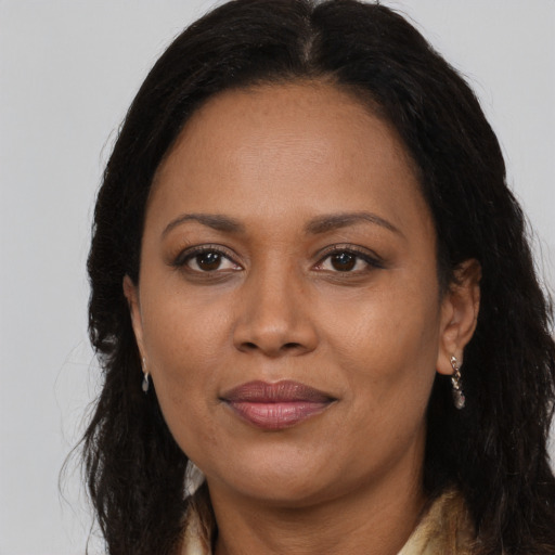 Joyful black adult female with long  brown hair and brown eyes