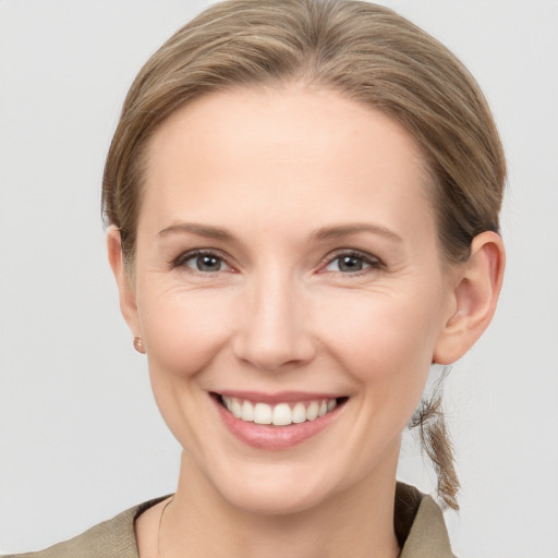 Joyful white young-adult female with medium  brown hair and grey eyes