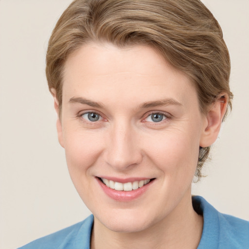 Joyful white young-adult female with short  brown hair and blue eyes