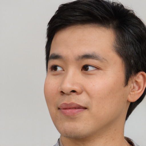 Joyful asian young-adult male with short  black hair and brown eyes