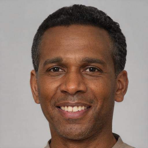 Joyful black adult male with short  black hair and brown eyes