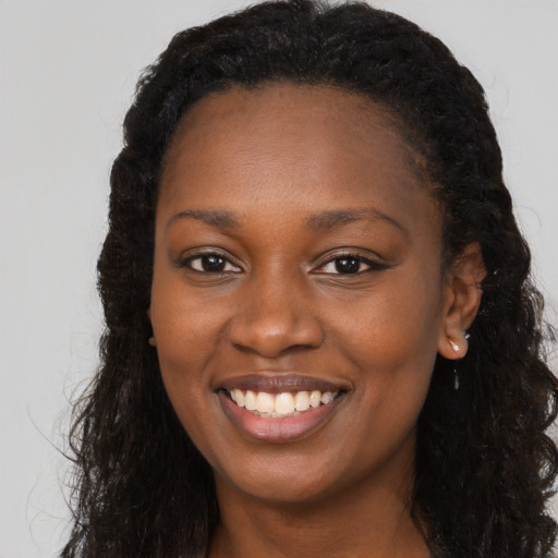 Joyful black young-adult female with long  brown hair and brown eyes