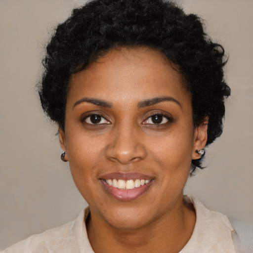 Joyful black young-adult female with short  black hair and brown eyes