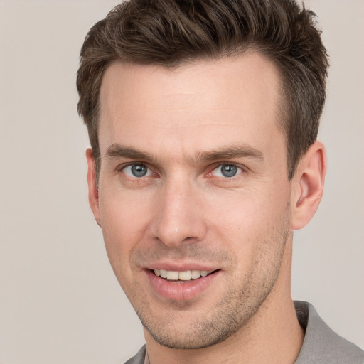 Joyful white young-adult male with short  brown hair and grey eyes