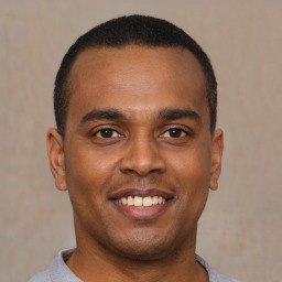 Joyful latino young-adult male with short  brown hair and brown eyes