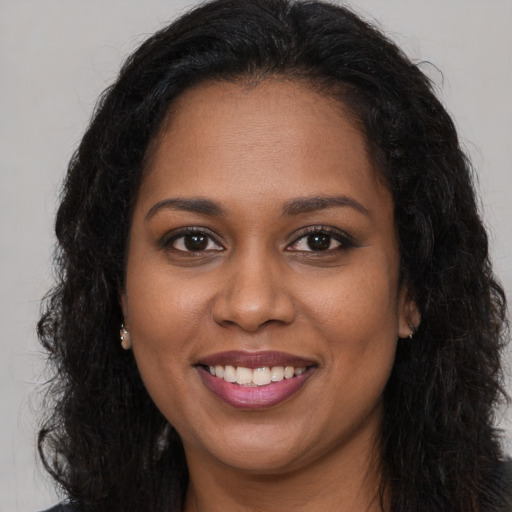 Joyful black young-adult female with long  brown hair and brown eyes