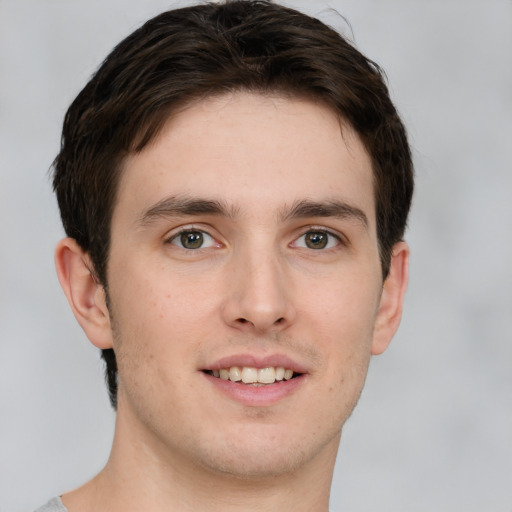 Joyful white young-adult male with short  brown hair and green eyes