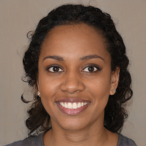 Joyful black young-adult female with medium  black hair and brown eyes