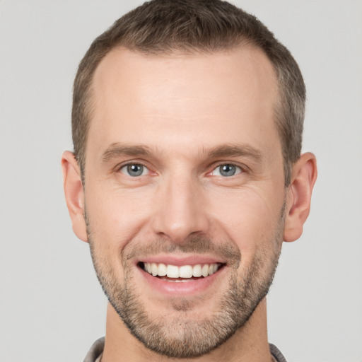 Joyful white young-adult male with short  brown hair and grey eyes