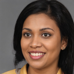 Joyful black young-adult female with long  brown hair and brown eyes