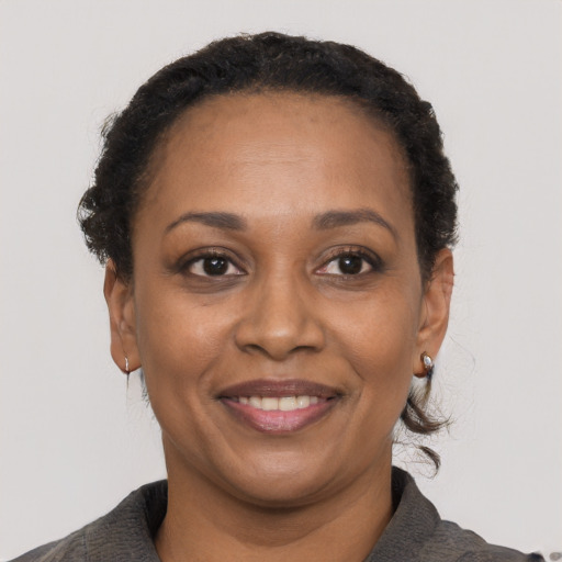 Joyful black adult female with short  black hair and brown eyes