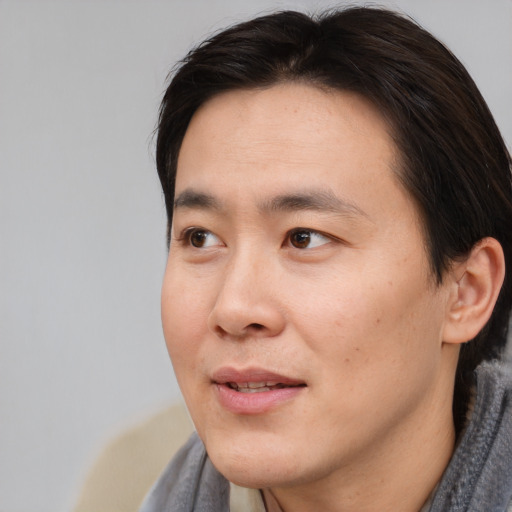 Joyful asian young-adult male with short  brown hair and brown eyes